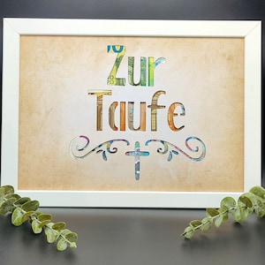 May include: A white framed picture with a brown background. The words "Zur Taufe" are cut out of the background and filled with colorful paper. A cross is cut out below the words.