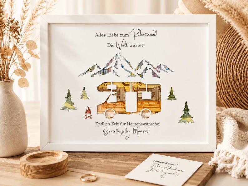 May include: A white framed print featuring a cutout camper van silhouette filled with folded currency, surrounded by watercolor illustrations of mountains, pine trees, and a campfire, with German text including Alles Liebe zum Ruhestand.
