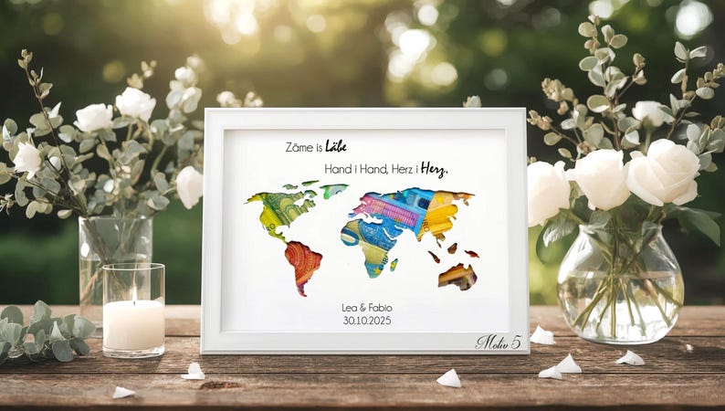 May include: A framed world map art print with colorful continents. The white frame surrounds the map, which has text at the top and bottom. The text reads "Zame is L&auml;be Hand i Hand, Herz i Herz. Lea & Fabio 30.10.2025".