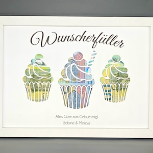 K&ouml;nnte beinhalten: Ein wei&szlig;er Bilderrahmen mit einem wei&szlig;en Passepartout und einem wei&szlig;en Hintergrund. Der Text "Wunscherf&uuml;ller" befindet sich oben im Rahmen. Drei Cupcake-Ausschnitte sind mit Geld gef&uuml;llt. Der Text "Alles Gute zum Geburtstag Sabine & Marcus" befindet sich unten im Rahmen.