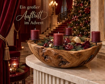 May include: A large, natural-edged wooden bowl filled with evergreen branches, red and gold ornaments, and four dark red pillar candles on black metal stands. The text "Ein großer Auftritt im Advent" is visible in the upper left corner.