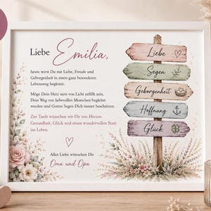 Puede incluir: Una impresi&oacute;n enmarcada en blanco con texto en alem&aacute;n para un bautizo, decorada con ilustraciones florales y un poste de madera. Los letreros muestran las palabras Liebe, Segen, Geborgenheit, Hoffnung y Gl&uuml;ck, acompa&ntilde;adas de iconos como un coraz&oacute;n, un ancla y un tr&eacute;bol.