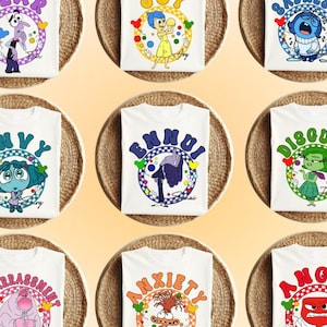 May include: Nine white t-shirts with colorful cartoon characters and text. The characters are from the movie Inside Out. The text on the shirts includes: Fear, Joy, Sadness, Envy, Ennui, Disgust, Embarrassment, Anxiety, and Anger.