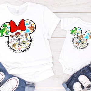 May include: A white t-shirt with a Mickey Mouse head design featuring characters from the Toy Story movie franchise. The text "You've Got A Friend In Me" is printed on the shirt. A white bodysuit with the same design is also shown.