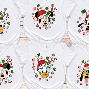 May include: Six white t-shirts with different Christmas-themed Disney characters. The characters include Mickey Mouse, Minnie Mouse, Donald Duck, and Goofy. Each character is wearing a Santa hat and reindeer antlers.