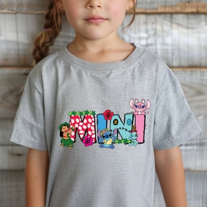 May include: Gray t-shirt with a colorful "MINI" graphic featuring Stitch and other characters from Lilo & Stitch. The graphic includes flowers, leaves, and a Hawaiian lei.