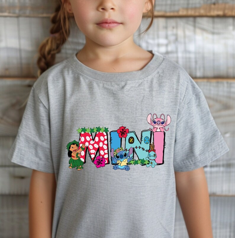May include: Gray t-shirt with a colorful "MINI" graphic featuring Stitch and other characters from Lilo & Stitch. The graphic includes flowers, leaves, and a Hawaiian lei.