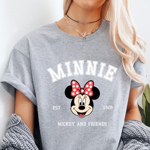 May include: Gray t-shirt with a white graphic of Minnie Mouse with red polka dots and the text "Minnie Est. 1928 Mickey and Friends".