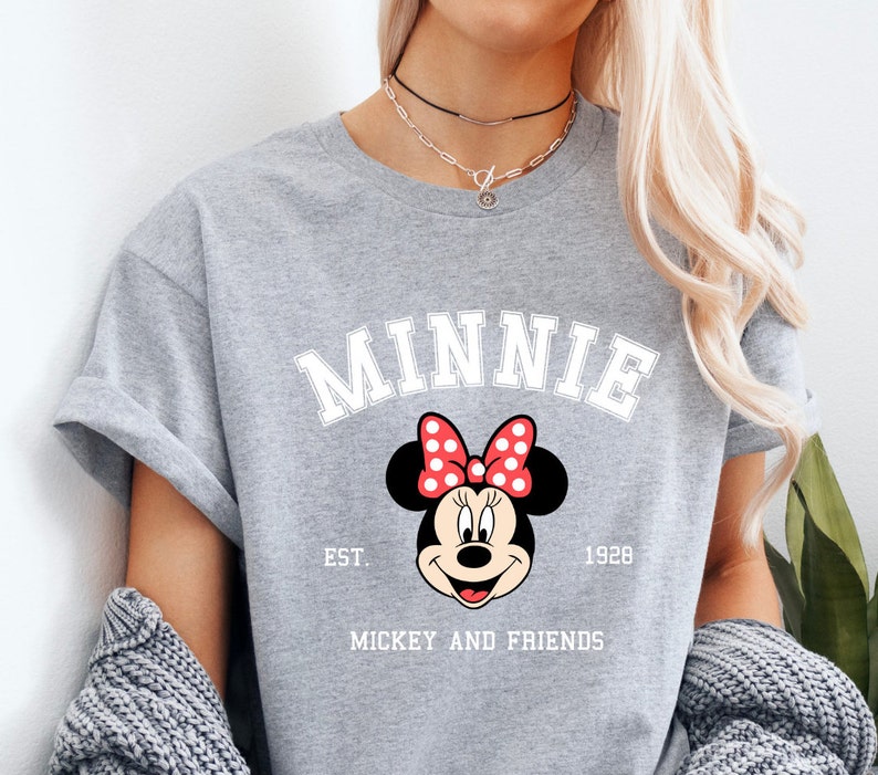 May include: Gray t-shirt with a white graphic of Minnie Mouse with red polka dots and the text "Minnie Est. 1928 Mickey and Friends".