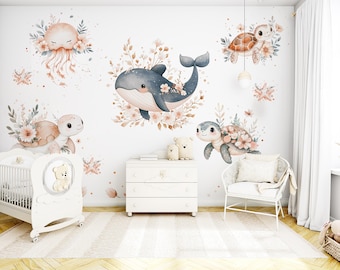 Könnte beinhalten: Ein Kinderzimmer mit einem weißen Kinderbett, einer Kommode und einem Stuhl. Die Wände sind mit Aquarellillustrationen eines Wals, Schildkröten und einer Qualle geschmückt, umgeben von floralen Akzenten. Der Raum hat eine weiche, pastellfarbene Farbpalette.