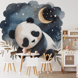 May include: A watercolor mural of a sleeping panda bear under a crescent moon and stars. The panda is resting on a branch against a dark blue night sky. A small white table and chairs are in front of the mural. A wooden play kitchen is to the right.
