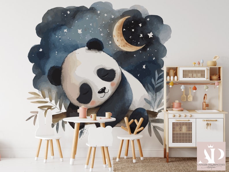 May include: A watercolor mural of a sleeping panda bear under a crescent moon and stars. The panda is resting on a branch against a dark blue night sky. A small white table and chairs are in front of the mural. A wooden play kitchen is to the right.