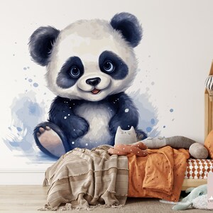 May include: A cute cartoon panda bear with black and white fur and blue eyes sits on a white background with blue watercolor splatters. The panda is smiling and has a pink nose.