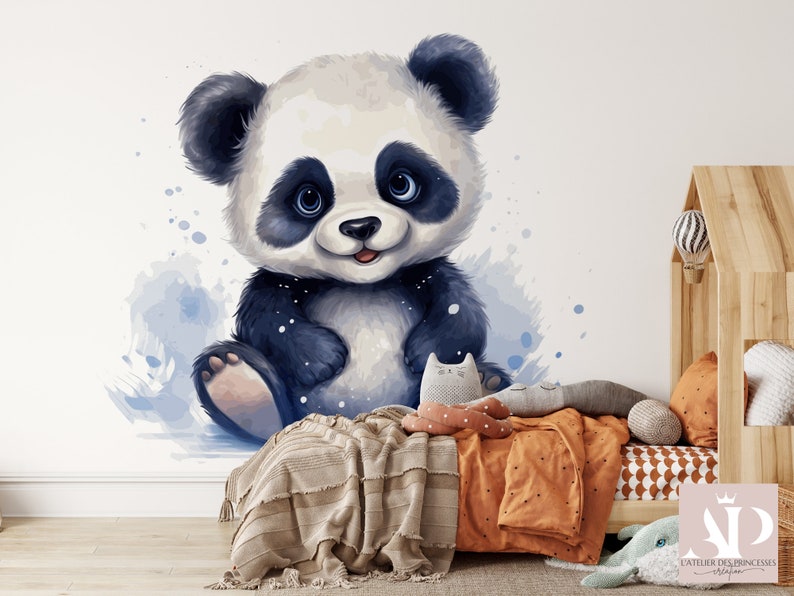 May include: A cute cartoon panda bear with black and white fur and blue eyes sits on a white background with blue watercolor splatters. The panda is smiling and has a pink nose.