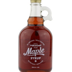 May include: A glass bottle with a handle filled with amber-colored maple syrup. The label reads "State of Vermont Pure Maple Syrup, All Natural - Wild-Crafted, Nutritious - 100% Pure, 33.8 fl oz - 1 Liter."