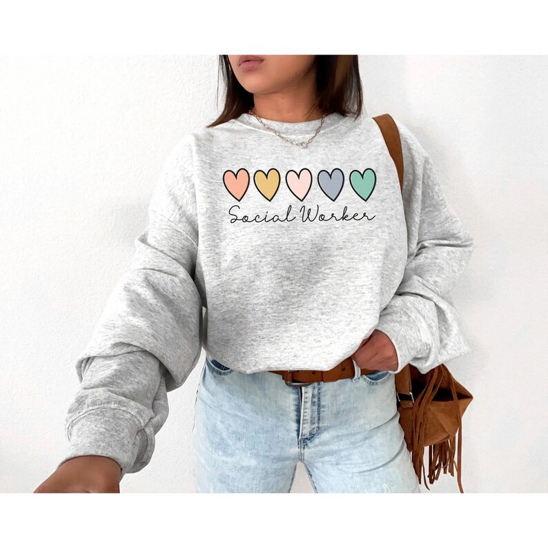 May include: A gray sweatshirt with a row of five colorful hearts and the text "Social Worker" printed on the front.