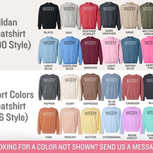 K&ouml;nnte beinhalten: Eine Tabelle mit verschiedenen Farboptionen f&uuml;r Gildan- und Comfort Colors-Sweatshirts. Die Sweatshirts zeigen das Wort "Hockey" auf der Vorderseite. Die Tabelle enth&auml;lt Farbnamen wie Schwarz, Asche, Heather Scarlet, Dunkel Heather, Sand, Milit&auml;rgr&uuml;n, Hellblau, Carolina Blau, Rotbraun, Hellrosa, Indigo Blau, Sicherheitsrosa, Pfeffer, Elfenbein, Espresso, Jeansblau, Scharlachrot, Schwarz, Yam, Pfirsich, Butter, Hortensie, Neonviolett und Kreideminze.