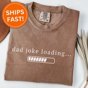 May include: Espresso-colored t-shirt with the text "dad joke loading..." and a loading bar graphic. The shirt is a Comfort Colors brand, size S-P-CH.
