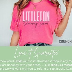 May include: A vibrant pink t-shirt featuring the text "LITTLETON Elementary School" in white. The top has short sleeves and a solid colour. The word "CRUNCHBERRY" is visible in the bottom right corner of the image.