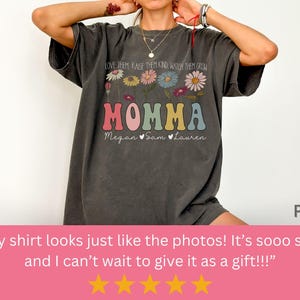 May include: A dark gray t-shirt with a floral design and the text "LOVE THEM RAISE THEM KIND WATCH THEM GROW MOMMA Megan Sam Lauren".