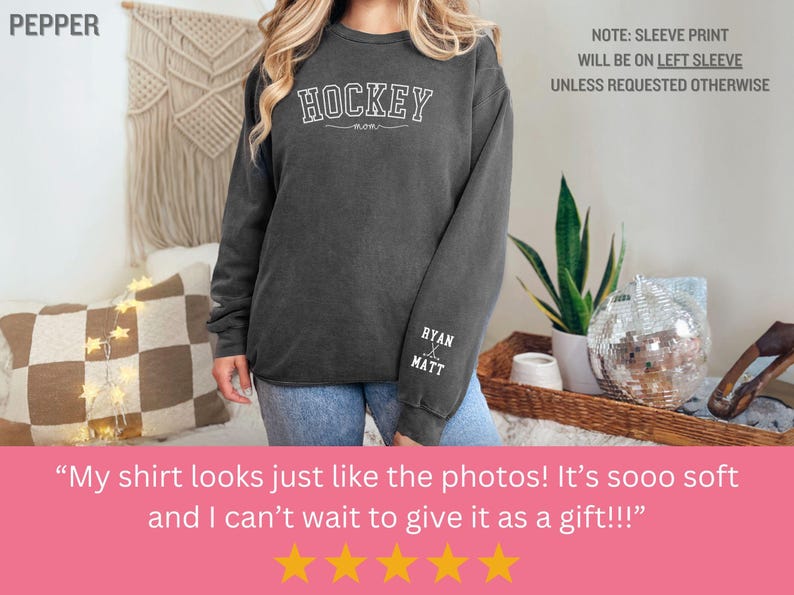 K&ouml;nnte beinhalten: Ein dunkelgrauer Pullover mit dem Wort "HOCKEY" auf der Vorderseite und den Namen "RYAN & MATT" auf dem linken &Auml;rmel. Der Pullover wird von einer Person getragen.