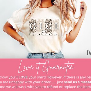Pode incluir: Camiseta cor marfim com a palavra "GIGI" em uma fonte decorativa, com os nomes "Megan", "Sarah" e "Lauren" abaixo. As letras s&atilde;o colocadas em padr&otilde;es de leopardo e florais. Uma fita preta est&aacute; centralizada sob a palavra "GIGI".