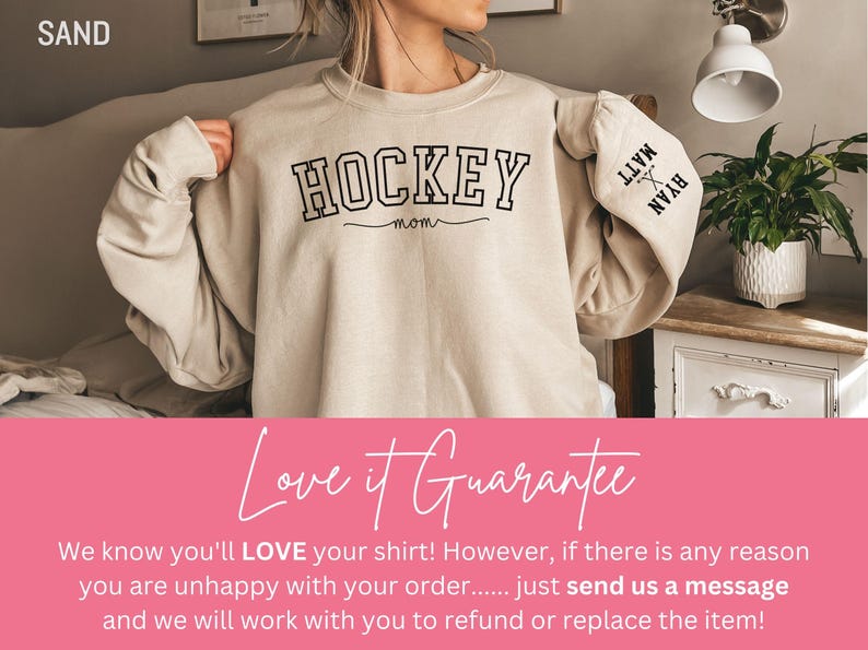 K&ouml;nnte beinhalten: Ein beiger Pullover mit dem Aufdruck "HOCKEY MOM" auf der Vorderseite. Die &Auml;rmel haben die Namen "MATT" und "RYAN" aufgedruckt.