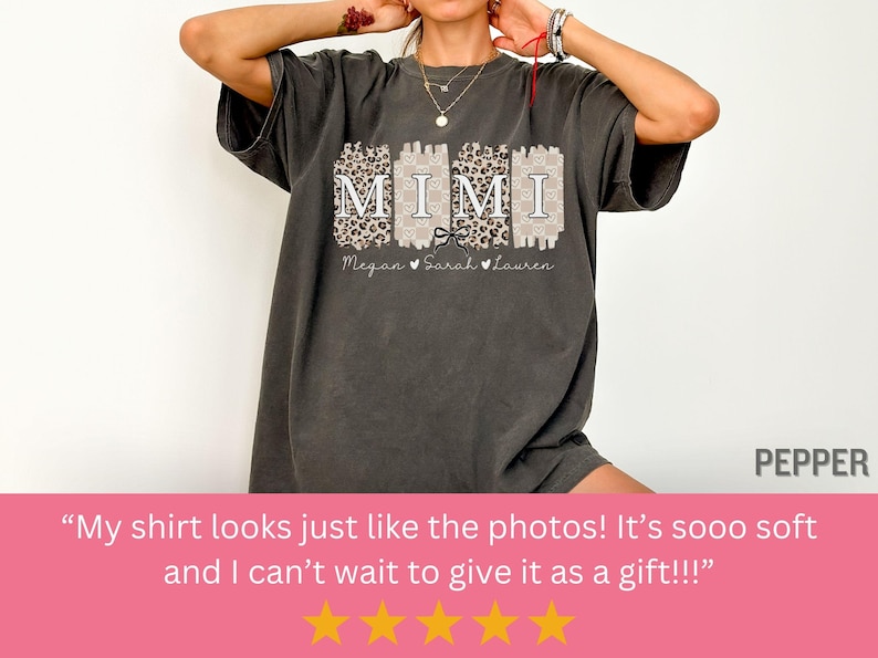 Może przedstawiać: Szary t-shirt z nadrukiem graficznym słowa "MIMI" białymi literami z czarną kokardką. Grafika jest otoczona wzorem w panterkę. Tekst "Megan Sarah Lauren" jest nadrukowany pod grafiką.