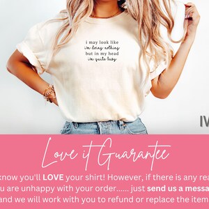 May include: Ivory-colored t-shirt with the text "i may look like i'm doing nothing but in my head i'm quite busy." The shirt is a neutral color and has a relaxed fit. The word "IVORY" is displayed on the right side.