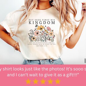 K&ouml;nnte beinhalten: Elfenbeinfarbenes T-Shirt mit dem Text "BUT SEEK FIRST HIS KINGDOM" und einem floralen Design. Das Shirt hat auch den Text "AND HIS RIGHTEOUSNESS AND ALL THESE THINGS WILL BE GIVEN TO YOU. MATTHEW 6:33."