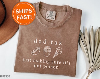 May include: Espresso-colored t-shirt with the text "dad tax" and the phrase "just making sure it's not poison". The shirt features white line drawings of a hot dog, fries, and an ice cream cone.