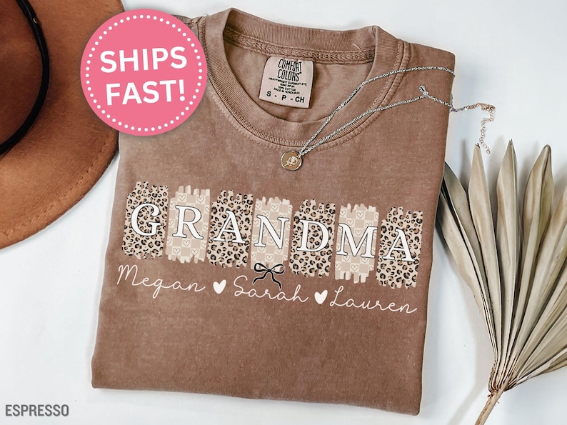 May include: Brown t-shirt with the word "Grandma" in a leopard print design. The names Megan, Sarah, and Lauren are written below the word "Grandma".
