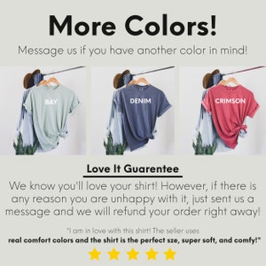 May include: Three t-shirts in different colours: bay, denim, and crimson. The shirts are folded and displayed on hangers. The text "More Colors!" and "Love It Guarantee" is visible. The text "Message us if you have another colour in mind!" is also visible. The text "I am in love with this shirt! The seller uses real comfort colours and the shirt is the perfect size, super soft, and comfy!" is visible. Five yellow stars are visible.