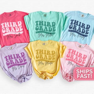 May include: A collection of six colorful t-shirts, each featuring the words "THIRD GRADE" in a retro font, a pencil graphic, and a teacher's name. Colors include pink, mint, light blue, lavender, yellow, and light pink.