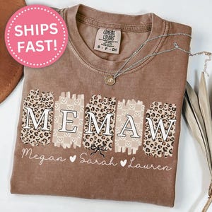 May include: A brown t-shirt with a "MEMAW" design featuring leopard print and hearts. The names Megan, Sarah, and Lauren are written below the design.
