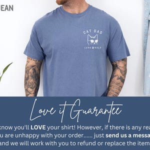 May include: Blue jean colored t-shirt with a white graphic of a cat wearing sunglasses and the text "CAT DAD" and "LUNA NALA". The shirt is made of a soft material.