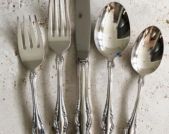 May include: Set of five silver-plated flatware pieces, including a knife, fork, and three spoons. The pieces have an ornate, floral design.