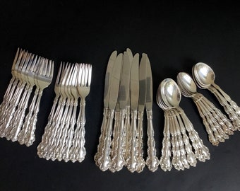 May include: A set of silverware with ornate handles. The set includes forks, knives, and spoons, all with a silver finish.