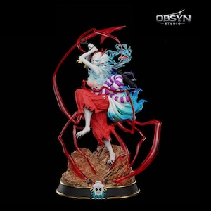 May include: A detailed figurine of a character in a dynamic pose, wielding a sword and surrounded by flowing red ribbons. The figure has white hair, red clothing, and a colorful, stylized design. The base is brown and black, with the "OBSYN STUDIO" logo visible.