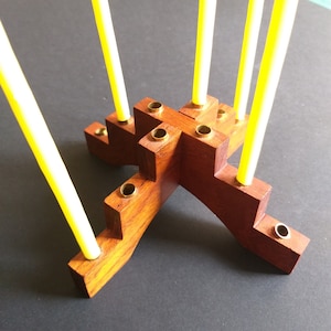 Puede incluir: Un portavelas de madera con seis portavelas de latón. El portavelas está hecho de madera oscura y tiene un diseño único. El portavelas está vacío y listo para ser usado.