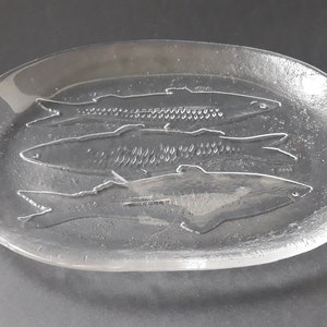 May include: A clear glass oval serving platter with three fish etched into the surface.