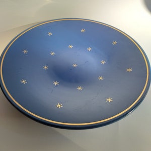 Può includere: Un piatto da portata in ceramica blu con un bordo dorato e un motivo di stelle dorate.
