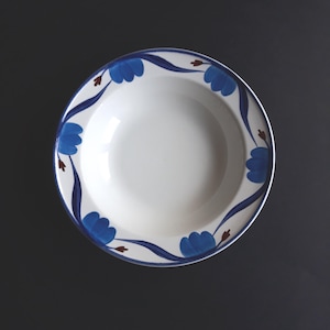 Könnte beinhalten: Weißer Keramiknapf mit blauem Blumenmuster am Rand. Die Blumen sind leuchtend blau, mit dunkelblauen Stielen und kleinen braunen Akzenten. Die Schüssel hat einen silbernen Rand und steht vor einem dunklen Hintergrund.