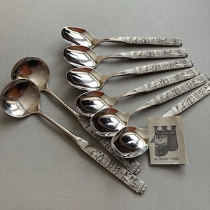 Può includere: Un set di cucchiai e mestoli color argento con manici ornati e incisi. I manici presentano motivi e figure dettagliate. È presente anche un piccolo cartellino con un disegno a corona e la scritta "KONGE-TINN MADE IN NORWAY".