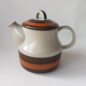 May include: A brown and orange striped ceramic teapot with a lid. The teapot has a rounded body and a handle.