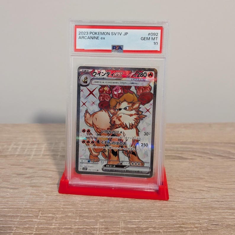 May include: A graded Pok&eacute;mon trading card featuring Arcanine ex from the 2023 SV1V JP set. The card is encased in a clear plastic holder and displayed on a red stand. The card's text includes "Arcanine ex" and Japanese characters.