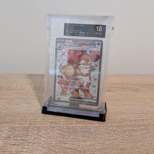 May include: A graded Pok&eacute;mon card in a clear protective case. The card features a detailed illustration of a fiery, canine-like creature. The card is graded a 10, with text in Japanese and English.