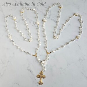 May include: White pearl rosary necklace with a gold cross and white rose accents. Also Available in Gold.