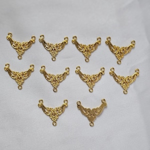 May include: Ten gold-tone metal decorative embellishments with intricate floral designs. The embellishments have three loops on the top for attaching to other jewelry or crafts.