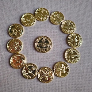 May include: A circle of 13 gold-colored tokens with various images, including a handshake, a cross, and a group of people. The tokens are arranged in a circle with a single token in the center.